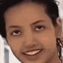 a close up of a woman 's face with a smile on her face and black hair .