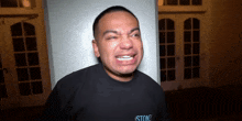 a man wearing a black shirt that says stone on it is crying