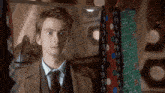 a man in a suit and tie is standing in front of a row of ties