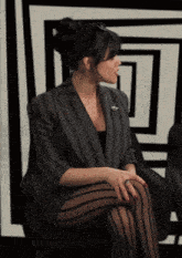 a woman wearing striped tights and a striped jacket sits in a chair