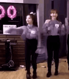 two women dancing in front of a sign that says idol