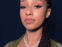 a close up of a woman 's face wearing a necklace and braids .