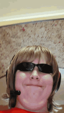 a person wearing sunglasses and a headset makes a funny face