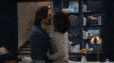 a man and woman kissing in front of a bookshelf with abc on the bottom right