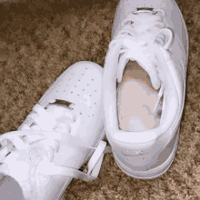 a pair of white nike air force 1 shoes on a brown carpet