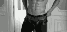 a black and white photo of a shirtless man taking off his pants .
