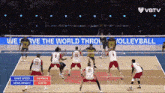 a volleyball game is being played in front of a sign that says we serve the world throu volleyball