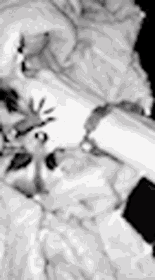 a black and white photo of a person laying on a bed with a remote control .