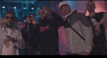 a group of men are posing for a picture and one of them is wearing a jacket with the word nike on it .