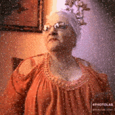 an elderly woman wearing glasses and a red top is standing in front of a window