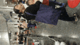a woman carrying a blue bag stands in front of a crowd of people