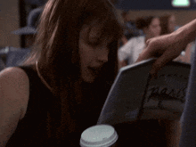 a woman is reading a book with the word paris on the cover