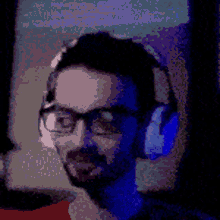 a man with glasses and headphones is sitting in front of a computer .