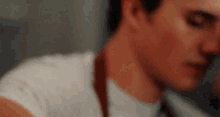a close up of a man 's face with his eyes closed . he is wearing an apron and a white shirt .