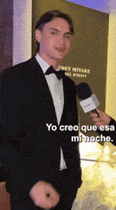 a man in a tuxedo is being interviewed by a microphone