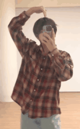 a man in a plaid shirt is taking a picture of himself with his phone