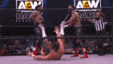 a wrestler is laying on the ground in front of a sign that says aew on it