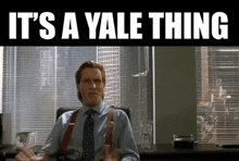 a man in a suit and tie is sitting at a desk with the words it 's a yale thing written above him .