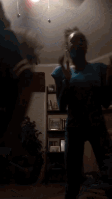a blurry picture of a person standing in a dark room with a ceiling fan