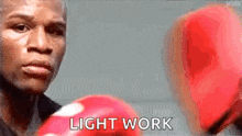 a boxer wearing red boxing gloves is looking at the camera and says `` light work '' .