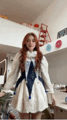 a girl with red hair is wearing a white dress and a blue top .