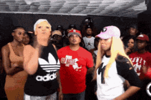 a woman wearing an adidas tank top stands in front of a crowd of people