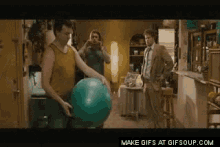 a man is holding a green exercise ball in a kitchen