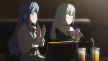 two anime girls sit at a table with drinks and a microphone