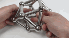 a person is playing with a metal toy that looks like a sphere