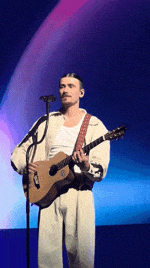 a man singing into a microphone while playing a guitar