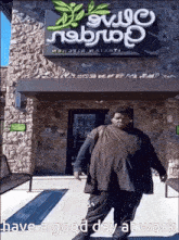 a man standing in front of a building that says olive