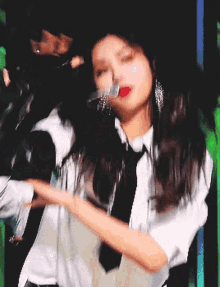 a woman in a white shirt and black tie is dancing on stage .