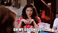 a woman in a red robe is sitting at a table with other people and says oh my goodness !!!