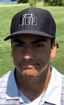 a young man wearing a black hat with a white letter m on it