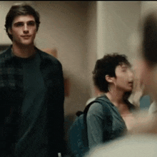 a man and a woman are standing next to each other in a hallway . the man is wearing a plaid shirt .