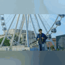 a man standing in front of a ferris wheel with a backpack