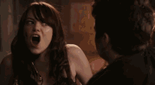 a woman is making a funny face while talking to a man in a dark room .