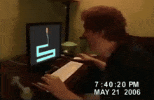 a man is typing on a keyboard in front of a computer monitor that says 7:40:20 pm may 21 2006