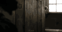 a man is peeking out of a door in a dark room .