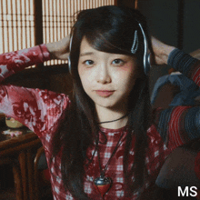 a woman wearing headphones and a plaid shirt with the letters ms on the bottom