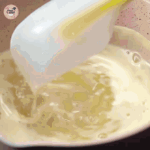 a spoon is being poured into a pot of liquid with a cake logo on the bottom