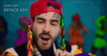 a man wearing a red hat and colorful braids is singing in front of a group of women .