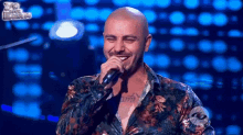 a man with a tattoo on his chest singing into a microphone while wearing a floral shirt