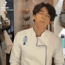 a man in a chef 's uniform is making a funny face with his eyes closed .