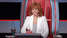 a woman sits in a chair with a nbc logo on the bottom right