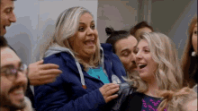 a woman in a blue jacket is surrounded by a group of people .
