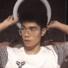 a man wearing glasses and headphones is sitting on a couch with a ring around his head .