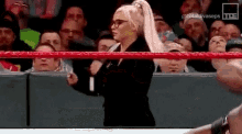 a woman is standing in a wrestling ring with a microphone .