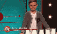 a young boy standing in front of a sign that says gustav wigelius vetlanda
