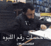 a man is sitting at a desk in front of a kor advertisement